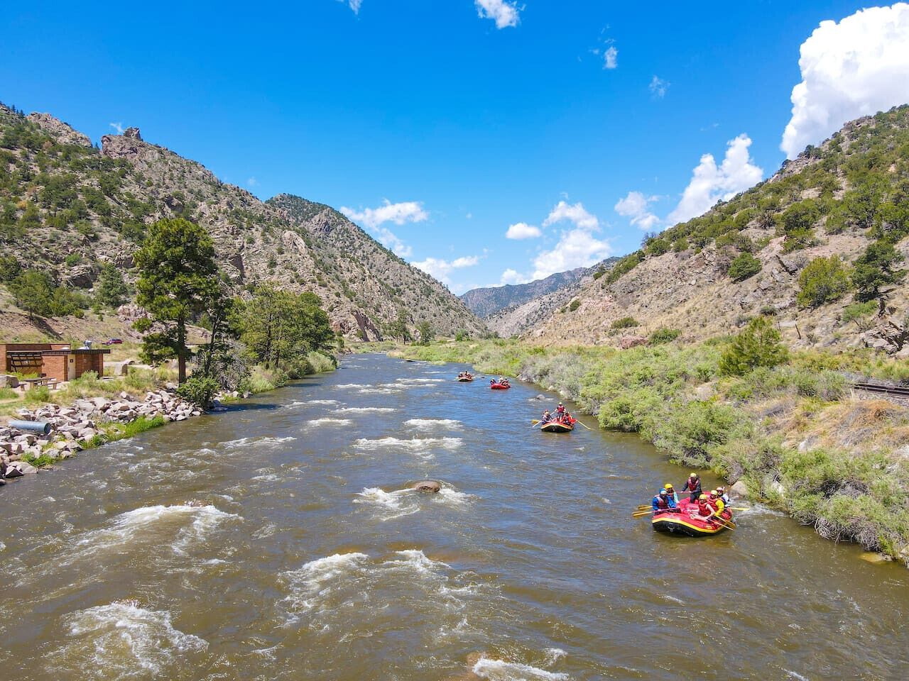 A river with rapids, surrounded by hills and a clear sky.