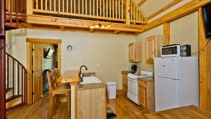 A compact kitchen with wooden cabinets, a sink, a stove, and a microwave. - Treehouse 3 - Mourning Dove Haus by Best Texas Travel (New Braunfels)