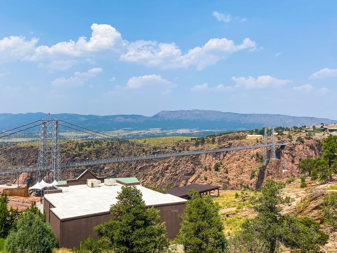 A suspension bridge over a rocky canyon with a mountainous backdrop.