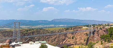 A suspension bridge over a rocky canyon with a mountainous backdrop.