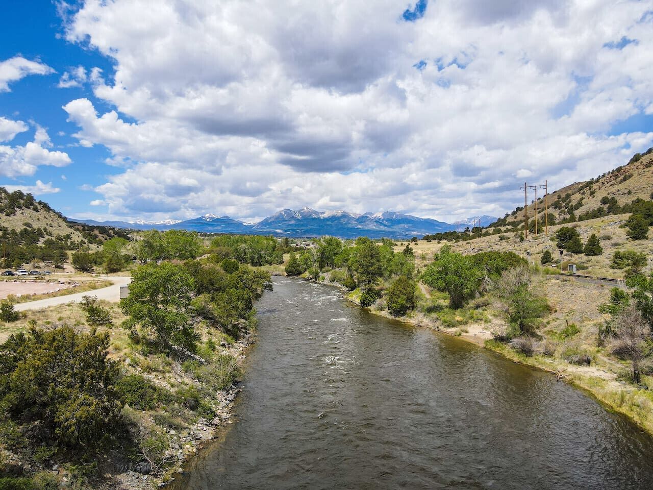 Une rivière qui traverse une vallée, avec des montagnes en arrière-plan.