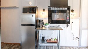 Une cuisine compacte équipée d’un réfrigérateur, d’un four à micro-ondes et d’un four encastré.