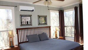 A bedroom with a wooden bed frame, two bedside tables, a ceiling fan, and a window with curtains. - Treehouse 5 - Robins Roost by Best Texas Travel (New Braunfels)