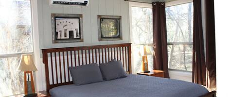 Een slaapkamer met een houten bedframe, twee nachtkastjes, een plafondventilator en een raam met gordijnen.