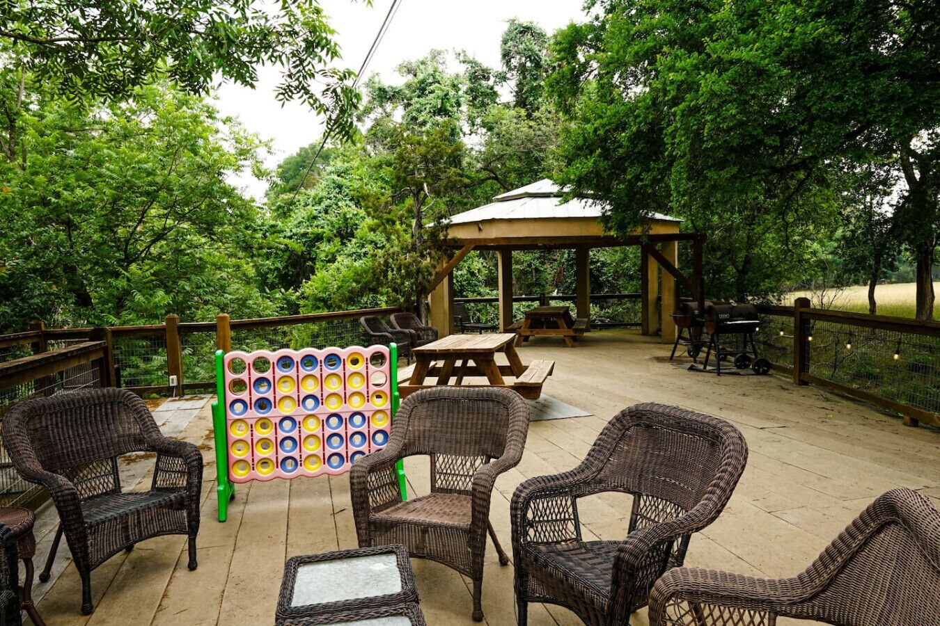 Un área de patio al aire libre con mobiliario de mimbre, una mesa de madera y un pabellón.