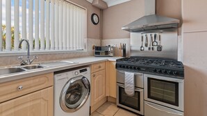 A compact kitchen with a built-in washer, oven, and stove. - Roslen - Lovely Bungalow Near Beach and Village (Saundersfoot)