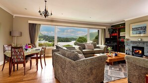 Una sala de estar con chimenea, un comedor con mesa y sillas, y vistas al exterior.