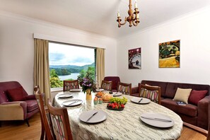 A dining area with a table set for four, a sofa, and a view of a lake. - Unerigg (Grasmere)