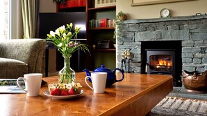 Una sala de estar acogedora con chimenea, una mesa de centro con una tetera, tazas y un plato de fresas.