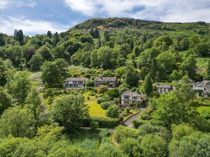A residential area with houses surrounded by lush greenery and a hill in the background. - Unerigg (Grasmere)