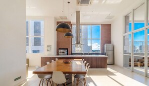 A modern kitchen with a dining area, large windows, and a city view. - MBC Edifício Metropolitan Barcelona (Goiânia)