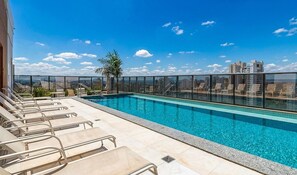 A rooftop pool with clear blue water, surrounded by lounge chairs and a city view. - MBC Edifício Metropolitan Barcelona (Goiânia)