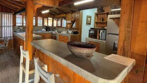 Une cuisine rustique avec des meubles en bois, un grand îlot central agrémenté d’un panier en osier et des appareils électroménagers modernes.