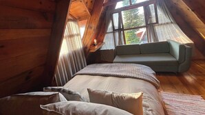 Une chambre confortable avec un lit, un canapé et une fenêtre avec des rideaux.