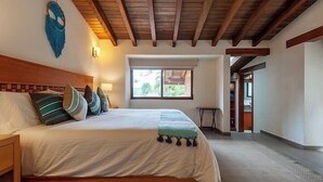A bedroom with a wooden bed, a window, and a door leading to another room. - Incredible Property with Huge Garden and Pool! (Valle de Bravo)