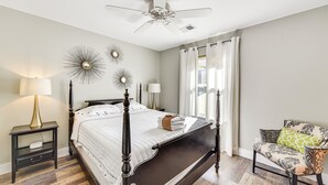 A bedroom with a four-poster bed, a nightstand with a lamp, a chair with patterned cushions, and decorative wall mirrors. - 1 Mi to Old Town: Cheerful Bluffton Townhome! (Bluffton)