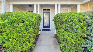 A two-story house with a front porch, a blue door, and a pathway flanked by hedges. - 1 Mi to Old Town: Cheerful Bluffton Townhome! (Bluffton)
