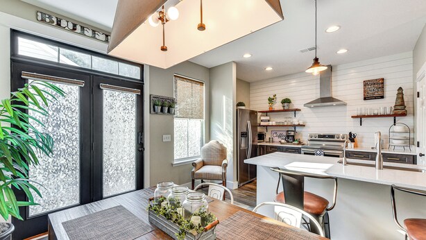 A modern kitchen with a central island, built-in appliances, and a dining area with a wooden table and chairs. - 1 Mi to Old Town: Cheerful Bluffton Townhome! (Bluffton)