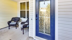 A front door with a blue exterior and a glass panel, flanked by two wicker chairs with cushions. - 1 Mi to Old Town: Cheerful Bluffton Townhome! (Bluffton)