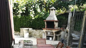 Un patio con un sendero empedrado, una mesa de madera y sillas.