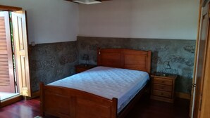 Un dormitorio con cama de madera, una mesita de noche, una lámpara y una pared con diseño de piedra.