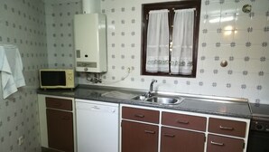 Una cocina compacta con lavavajillas integrado, microondas y un lavabo.