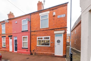 A two-story red brick building with a white door and windows, a satellite dish, and a sign reading 'OXFORD ST.'