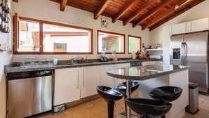 A modern kitchen with a central island, stainless steel appliances, and a view of the outdoors. - Casa Male (Valle de Bravo)