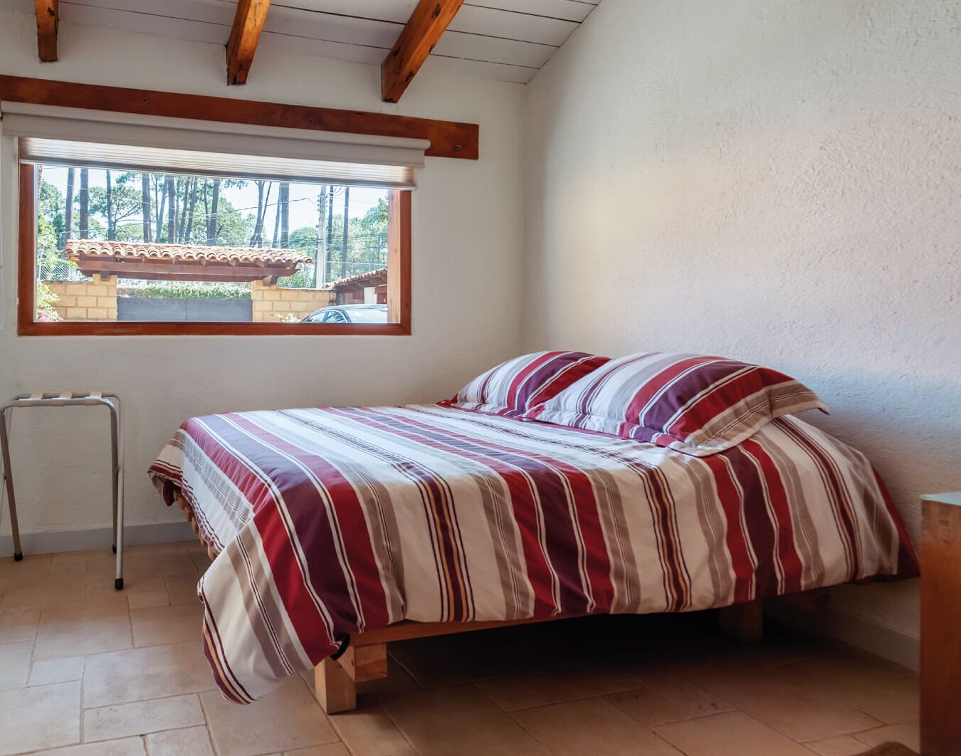 Un dormitorio con una cama, una ventana y techo de madera.