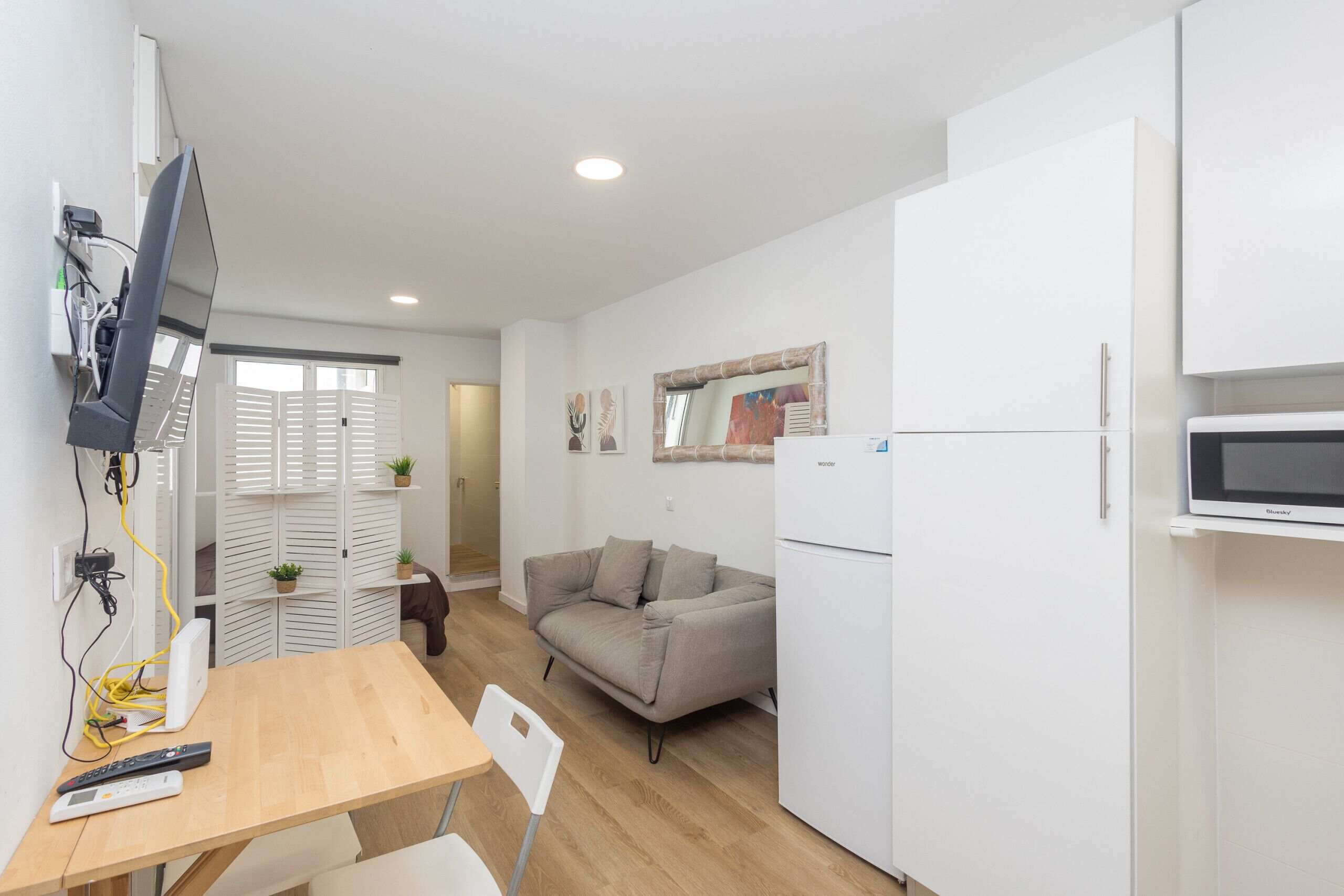 Una cocina compacta con comedor, sofá y televisión.