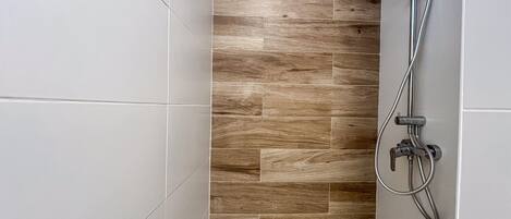 A shower area with a wooden panel wall and a modern showerhead.