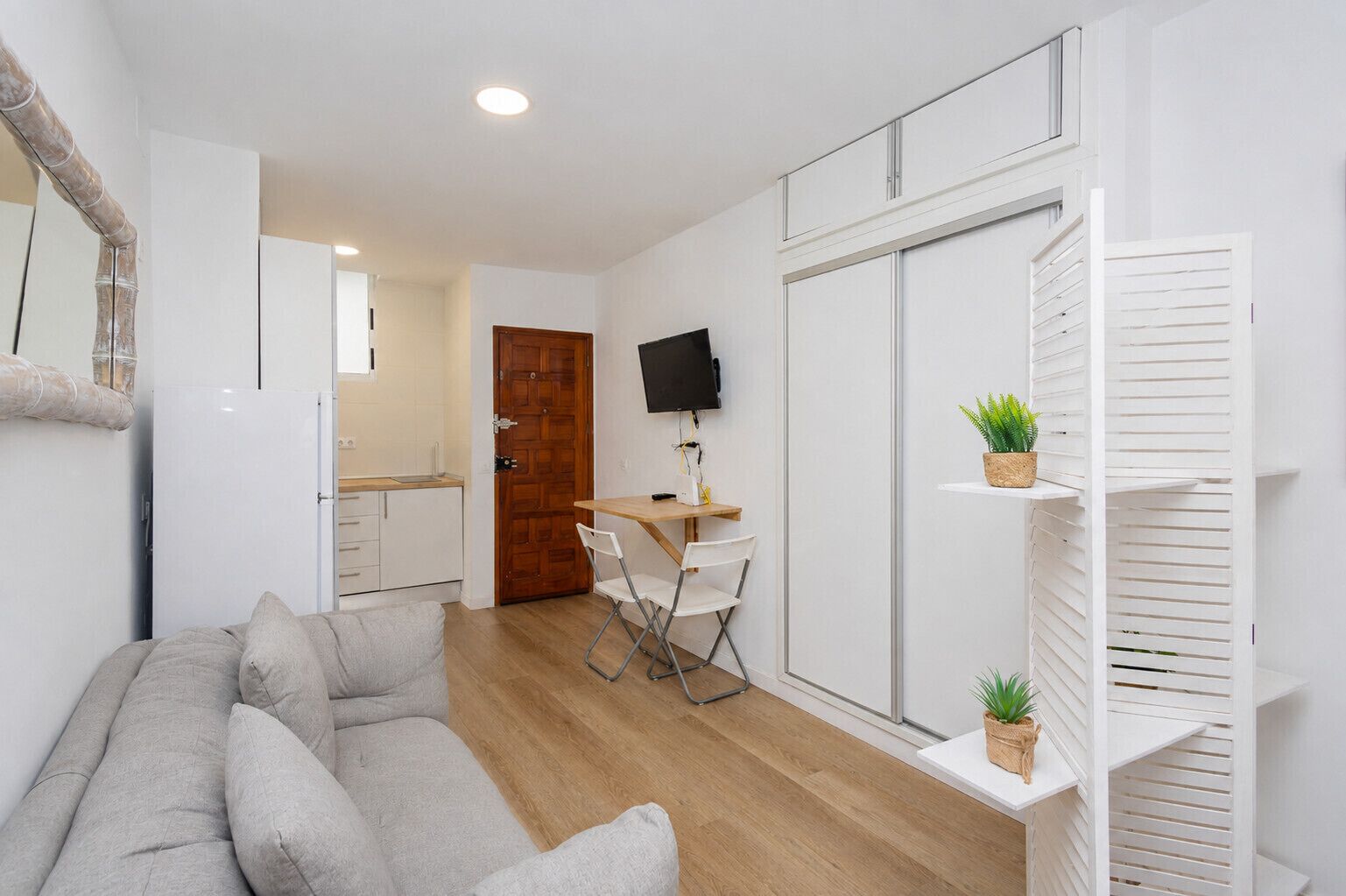 Un espacio habitable pequeño con sofá, una mesa de comedor con sillas, televisor y cocina.