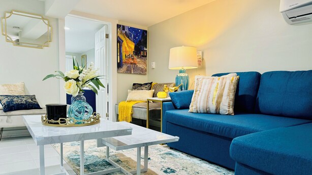 Ein Wohnzimmer mit einem blauen Sofa, einem weißen Couchtisch, einem Spiegel und einem Bild an der Wand.