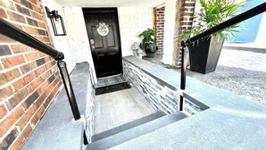 Ein Backsteinhaus mit schwarzem Eingang, Fußmatte und einer Topfpflanze.