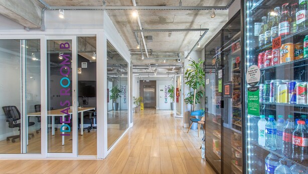 Ein Büro mit Glaswänden, Holzboden und einem Getränkeautomaten.