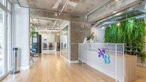 Ein Büro mit Empfangsbereich, Holzboden, Deckenventilator und einer grünen Wand mit Pflanzen.