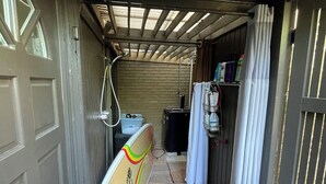 A narrow hallway with a surfboard leaning against the wall, a shower area with a curtain, and a door leading to a garage. - Siesta Key Newly Renovated Condo with Private Beach/short walk to Siesta Village (Siesta Key)