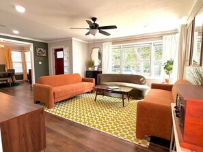 Una sala de estar con un sofá, sillones, una mesa de centro y un tapete estampado.