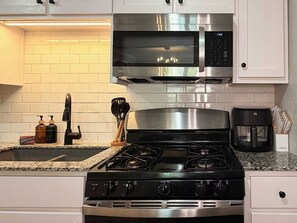 A kitchen with a stainless steel stove, a microwave, and a coffee maker.