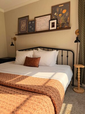 A neatly made bed with a patterned blanket, a brown pillow, and a headboard.