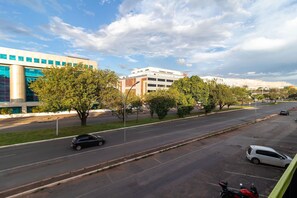 Un immeuble à étages doté d’une architecture moderne, avec de grandes fenêtres et un parking où sont stationnées plusieurs voitures.