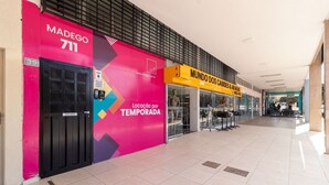 A shopping mall corridor with a brightly colored store named 'MUNDO DOS CABIDEI & ARAS' and a store named 'MADEGO 711'.