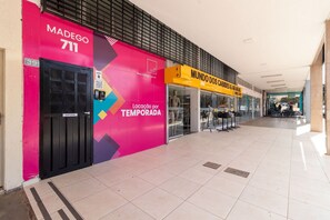 Un couloir d’un centre commercial, avec une boutique aux couleurs vives appelée « MUNDO DOS CABIDEI & ARAS » et une autre boutique appelée « MADEGO 711 ».