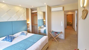 A hotel room with a bed, a mirror, a small table, and a door leading to a hallway.