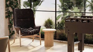A cozy room with a dark armchair, a round wooden table, and a foosball table. - Cozy studio at Westwood By IMTIAZ (Dubai)