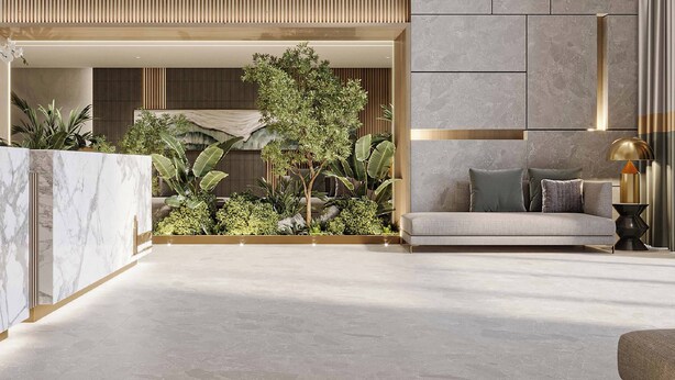 A modern lobby with a marble reception desk, a sofa with cushions, and a potted plant arrangement. - Cozy studio at Westwood By IMTIAZ (Dubai)
