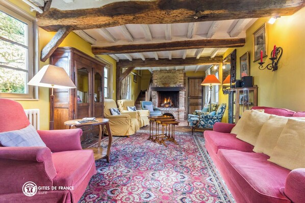 A cozy living room with a fireplace, wooden beams, and comfortable seating.