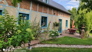 Ein traditionelles Backsteinhaus mit blauen Fensterrahmen und einem gepflegten Garten.
