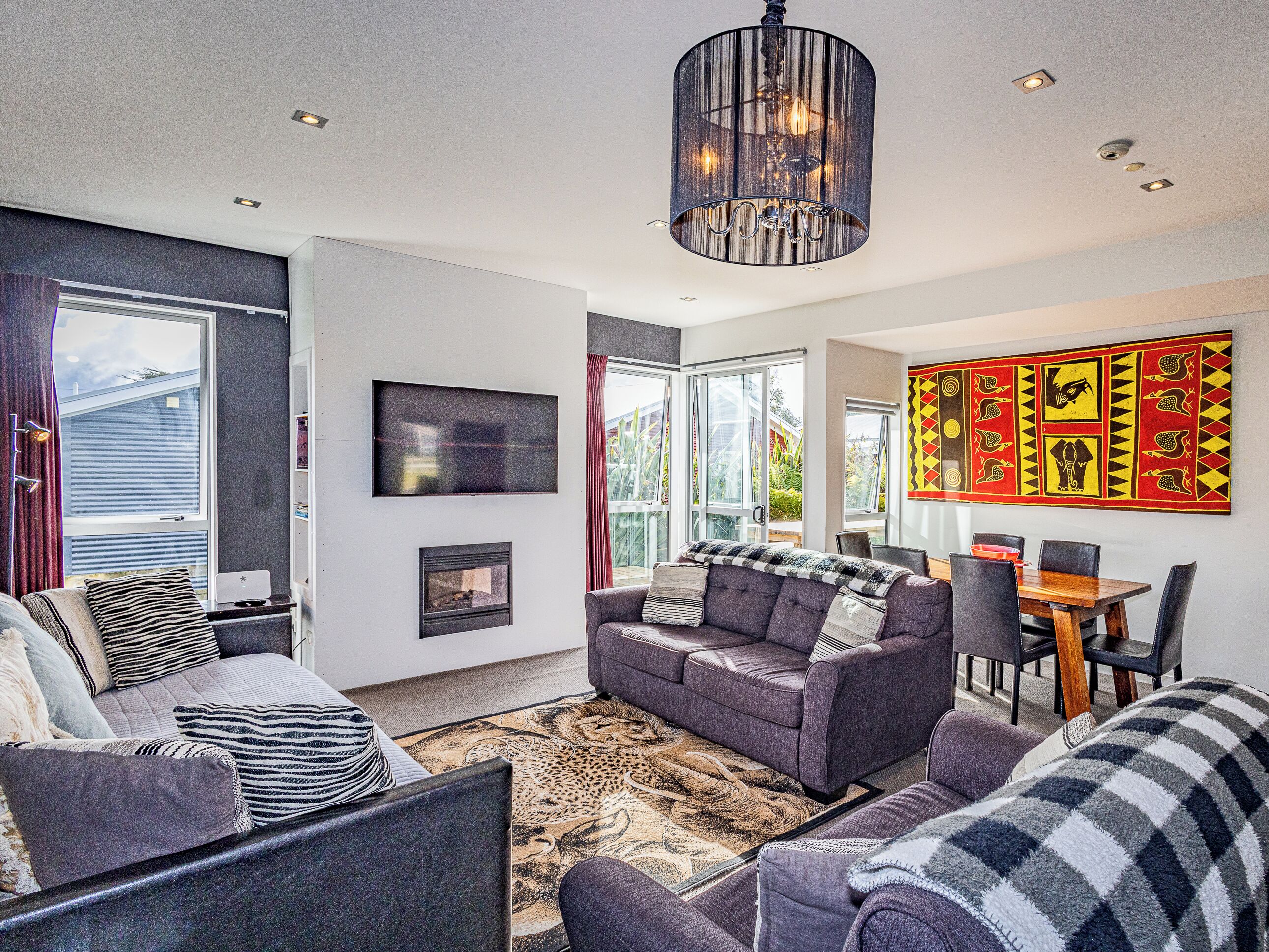 A modern living room with a fireplace, sofa, and dining area.