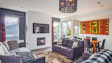 A modern living room with a fireplace, sofa, and dining area.
